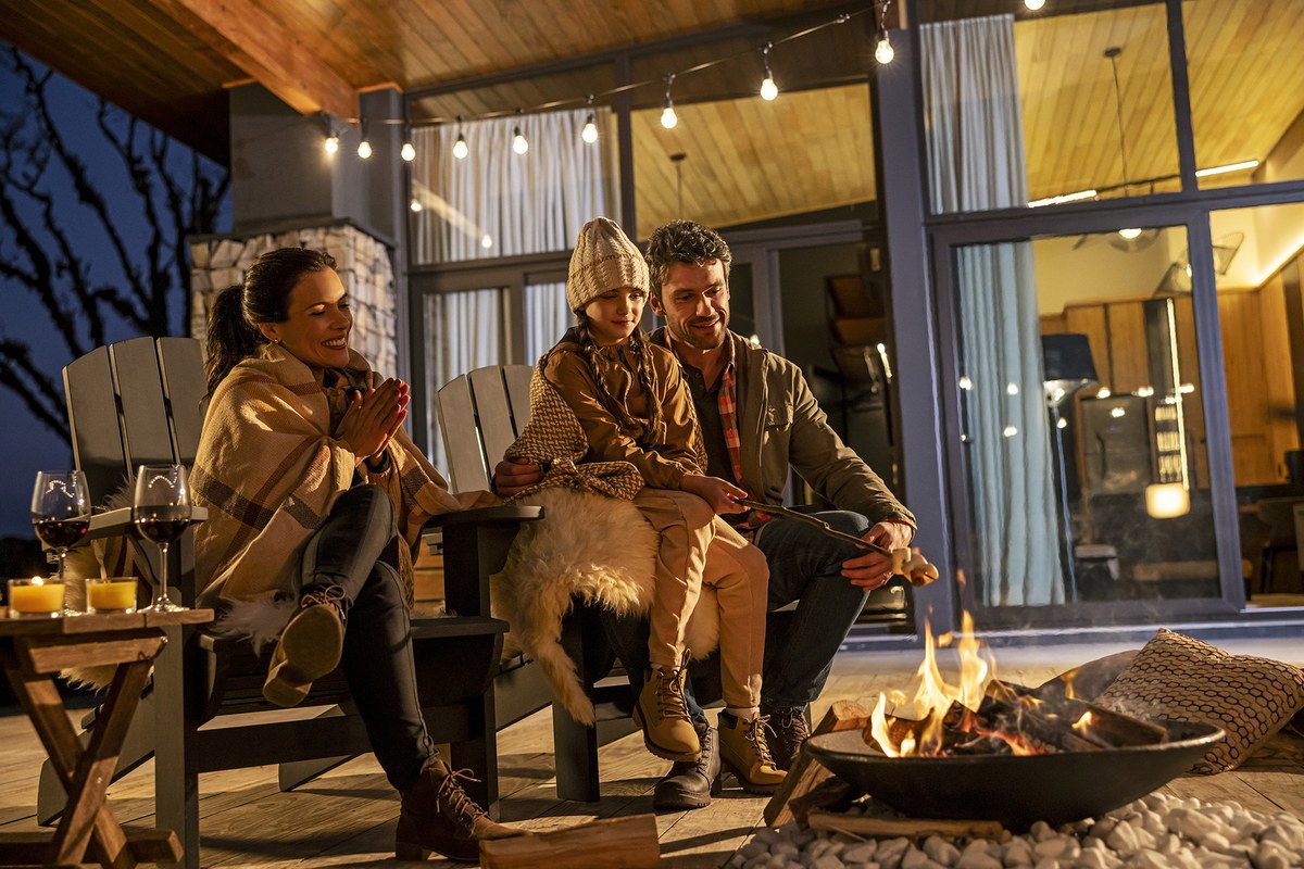 Família reunida ao redor da lareira externa à noite com taças de vinho