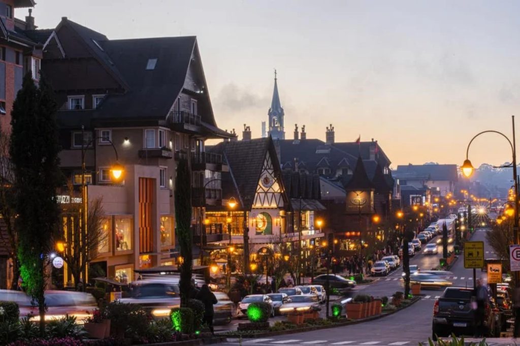 Rua principal de Gramado ao entardecer com arquitetura europeia e luzes quentes